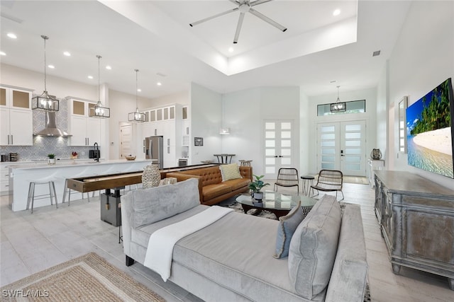 living room with a towering ceiling, a tray ceiling, and ceiling fan