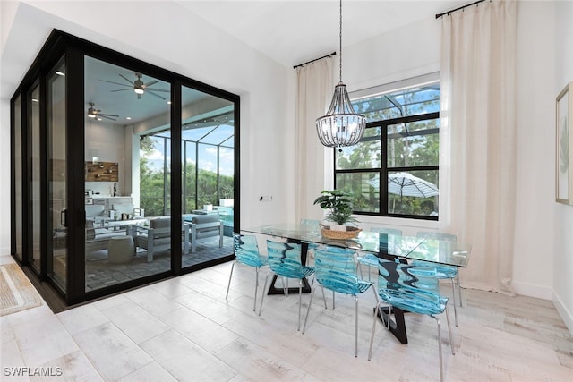 dining area with ceiling fan with notable chandelier, a wealth of natural light, and light hardwood / wood-style flooring