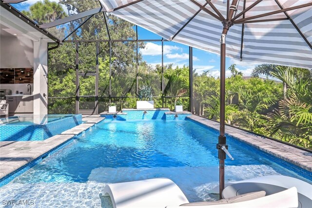 view of pool with glass enclosure, sink, pool water feature, and a patio area