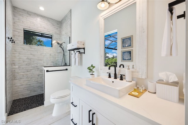 bathroom featuring a healthy amount of sunlight, tiled shower, and vanity