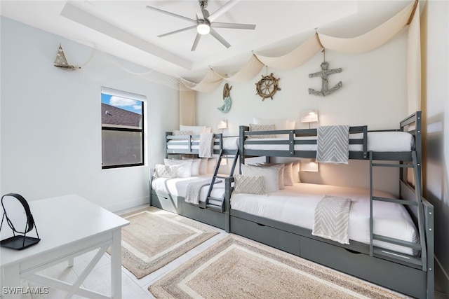 bedroom with ceiling fan and a tray ceiling