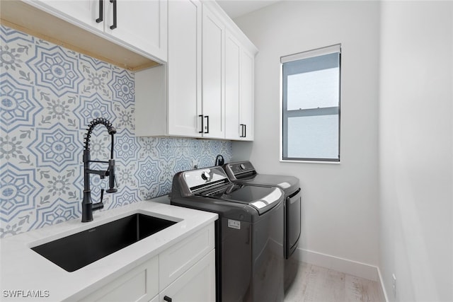 laundry room featuring cabinets, light wood-type flooring, sink, and washing machine and dryer