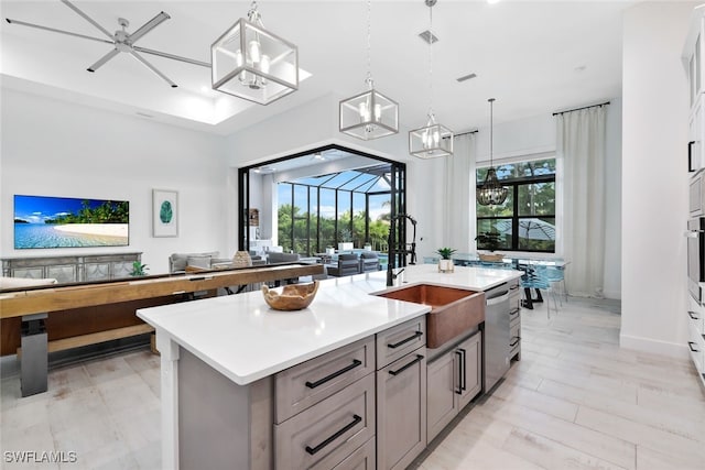 kitchen featuring an island with sink, hanging light fixtures, sink, and a wealth of natural light