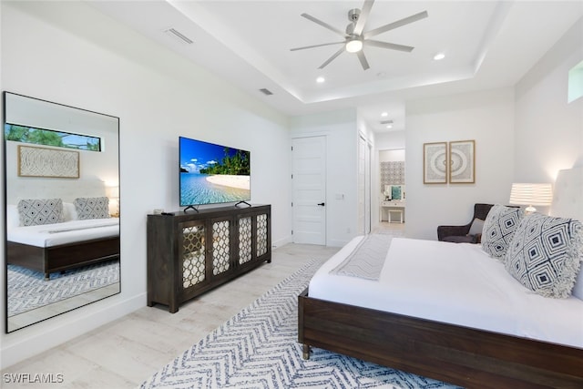 bedroom featuring ceiling fan, a raised ceiling, and light hardwood / wood-style floors