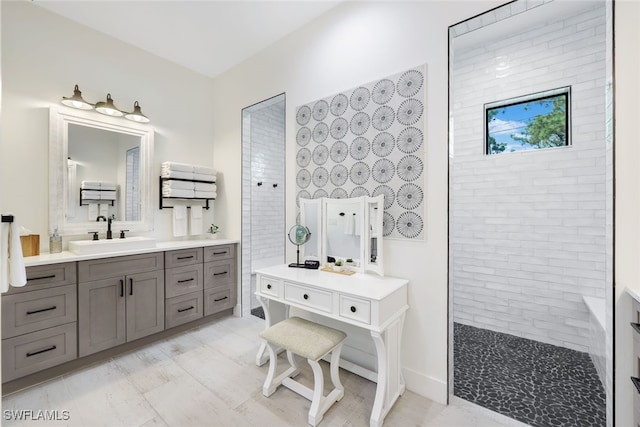 bathroom featuring a tile shower and vanity