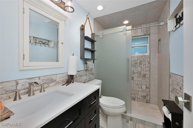 bathroom featuring tiled shower, vanity, toilet, and tile walls