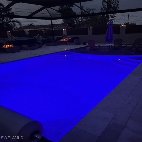 view of swimming pool featuring glass enclosure, a patio, and an outdoor fire pit