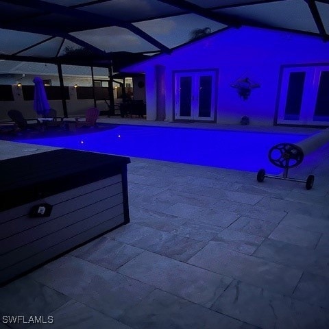 view of swimming pool with french doors, glass enclosure, and a patio area