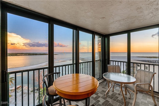 sunroom / solarium featuring a water view and a view of the beach