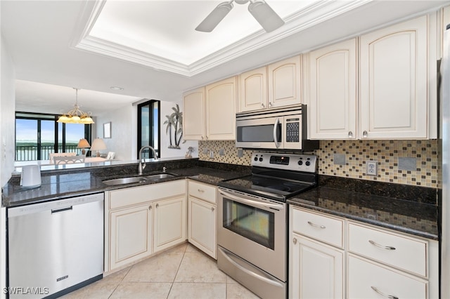 kitchen with hanging light fixtures, dark stone countertops, ceiling fan with notable chandelier, stainless steel appliances, and sink