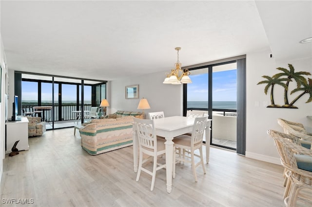 dining space with an inviting chandelier, light wood-type flooring, a water view, and expansive windows