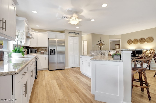 kitchen with stainless steel appliances, a kitchen island, light hardwood / wood-style flooring, and white cabinetry