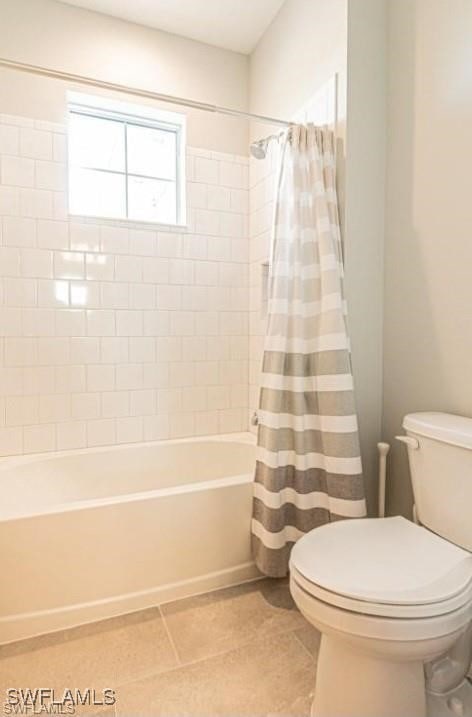 bathroom featuring shower / tub combo with curtain, tile patterned floors, and toilet