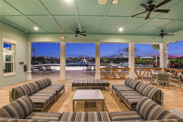 patio terrace at dusk featuring ceiling fan, an outdoor hangout area, and a water view