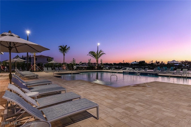 pool at dusk featuring a patio area