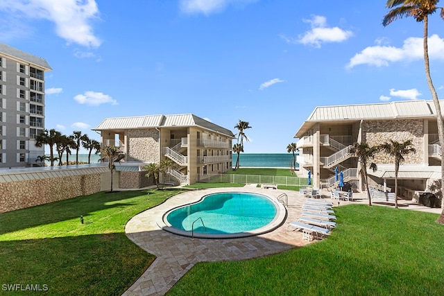 view of swimming pool with a yard, a water view, and a patio area