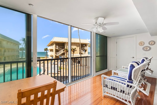 sunroom with ceiling fan and a water view