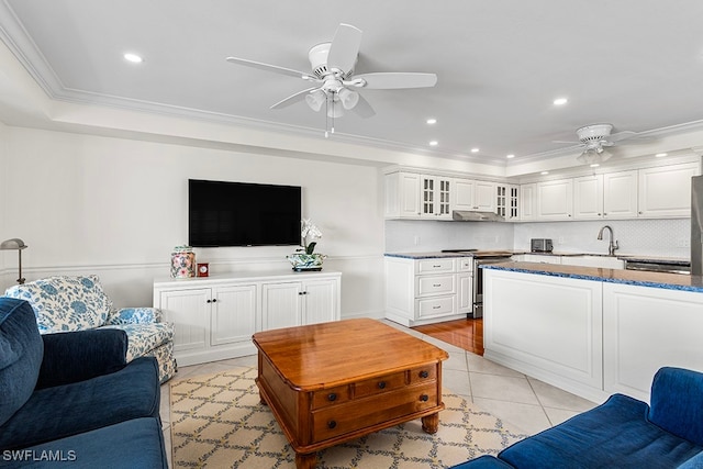 living room featuring ceiling fan, sink, light tile patterned floors, and crown molding