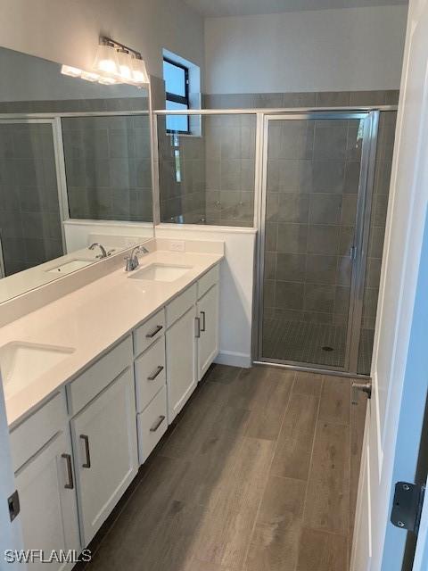 bathroom with wood-type flooring, vanity, and a shower with shower door