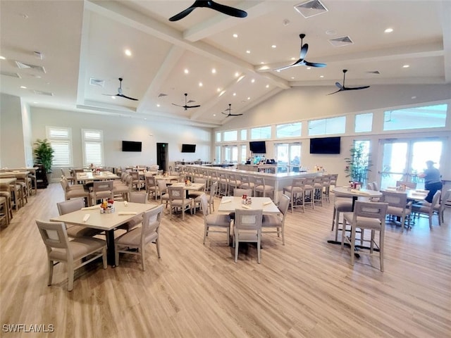 dining area with high vaulted ceiling and light hardwood / wood-style flooring