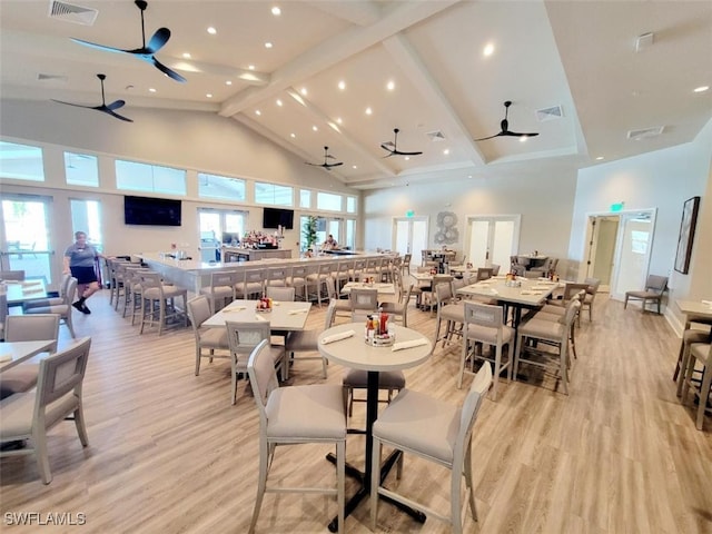 dining space featuring ceiling fan, high vaulted ceiling, and light hardwood / wood-style flooring