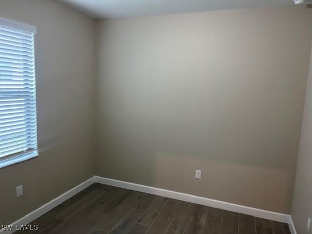 empty room with dark hardwood / wood-style flooring and plenty of natural light