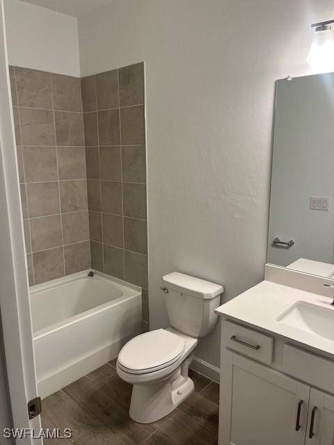 full bathroom featuring vanity, hardwood / wood-style flooring, toilet, and tiled shower / bath