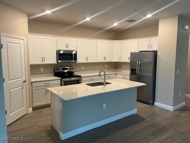 kitchen with white cabinets, stainless steel appliances, a center island with sink, and sink