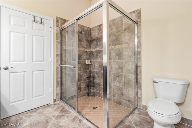 bathroom featuring toilet, tile patterned flooring, and a shower with door