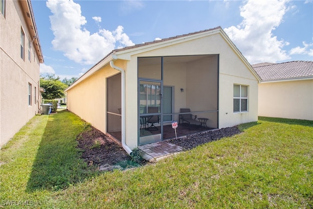 back of property featuring a yard, a sunroom, and a patio area