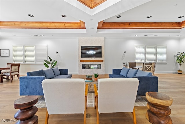 living room featuring a wealth of natural light, beam ceiling, and light hardwood / wood-style floors