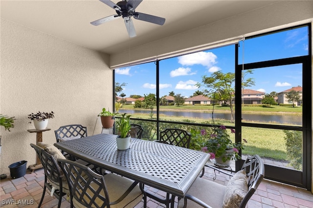 sunroom featuring ceiling fan and a water view