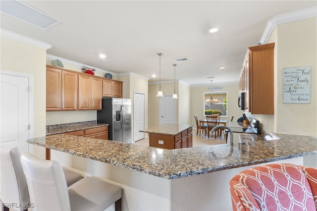 kitchen featuring hanging light fixtures, ornamental molding, stainless steel appliances, a center island, and dark stone countertops