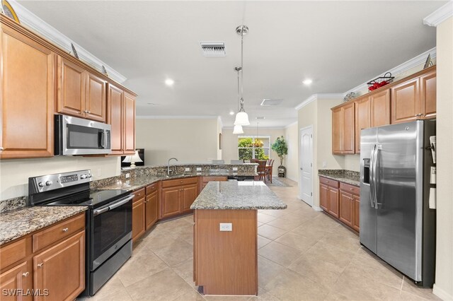 kitchen featuring appliances with stainless steel finishes, hanging light fixtures, light stone counters, a center island, and ornamental molding