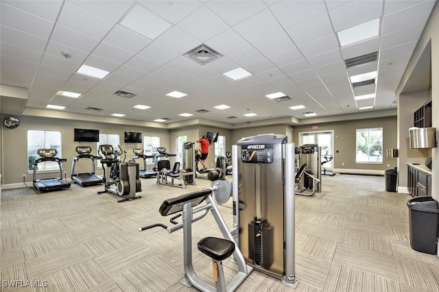 gym with a paneled ceiling and light colored carpet