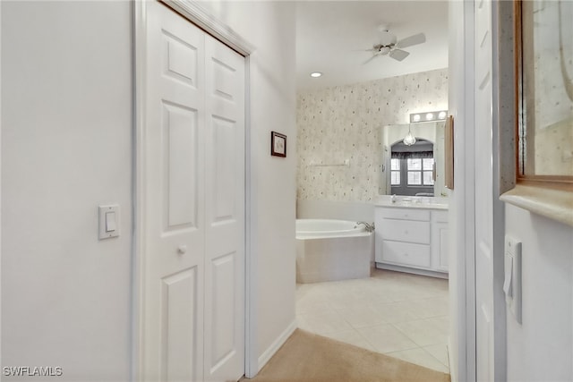 bathroom with a relaxing tiled tub, tile patterned flooring, ceiling fan, and vanity