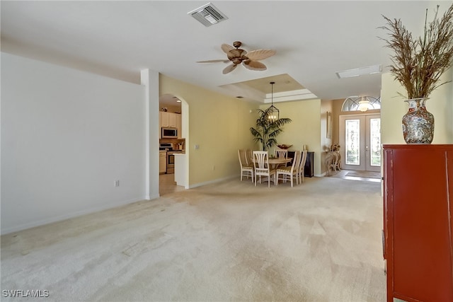 unfurnished room featuring light colored carpet, a raised ceiling, ceiling fan, and french doors