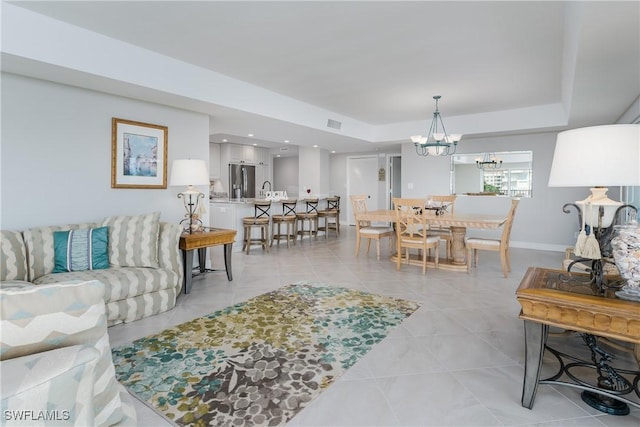 1036 S Collier Blvd Unit B-301, Marco Island, FL 34145 - living room featuring a chandelier, a raised ceiling, baseboards, and light tile patterned floors