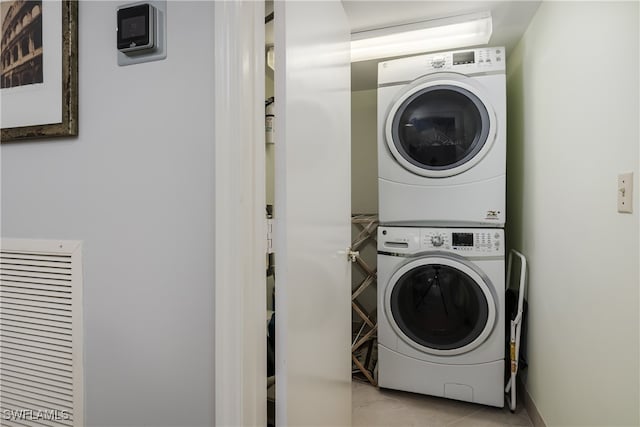 clothes washing area featuring light tile patterned flooring and stacked washer and dryer