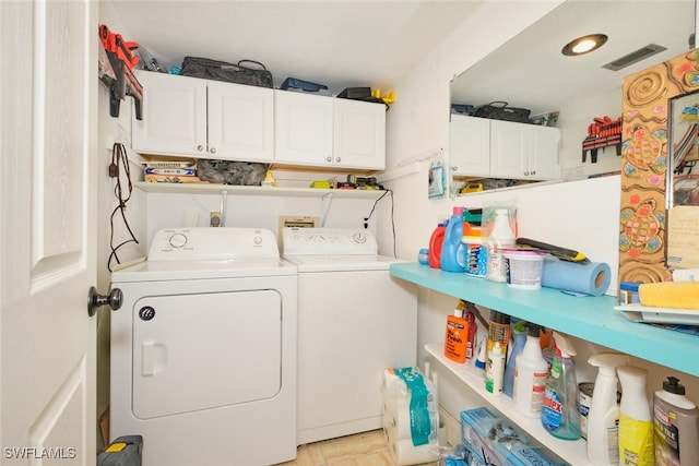 laundry room with washer and clothes dryer, visible vents, and cabinet space