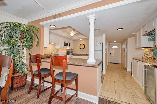 kitchen featuring ornate columns, ceiling fan, white appliances, and beverage cooler
