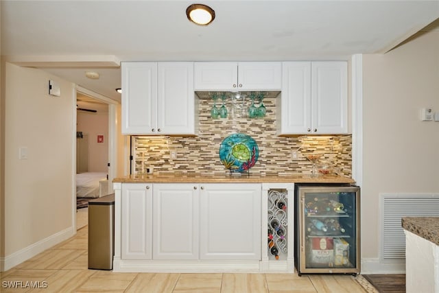 kitchen with white cabinets, tasteful backsplash, wine cooler, and visible vents