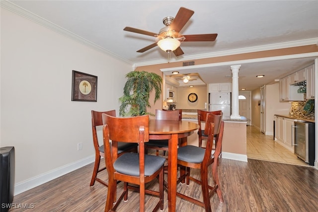 dining space with crown molding, beverage cooler, visible vents, ceiling fan, and ornate columns