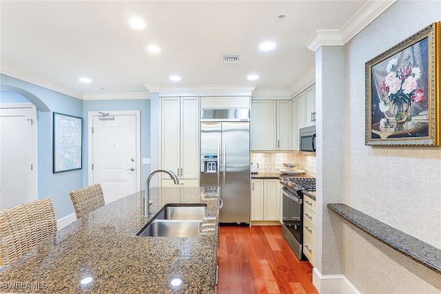 kitchen with sink, white cabinetry, dark stone countertops, ornamental molding, and appliances with stainless steel finishes