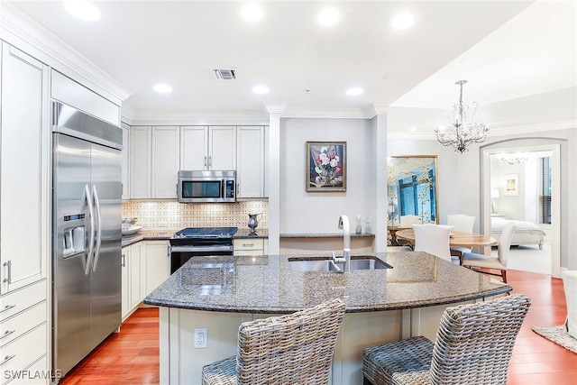 kitchen with stainless steel appliances, hanging light fixtures, sink, and dark stone countertops