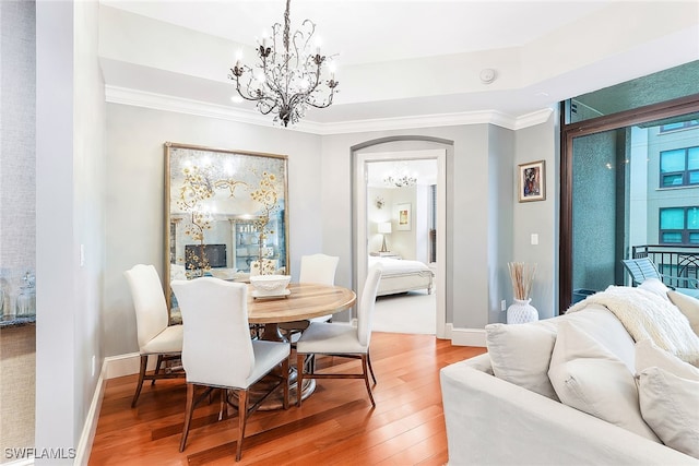 dining room featuring hardwood / wood-style floors, ornamental molding, a raised ceiling, and a chandelier