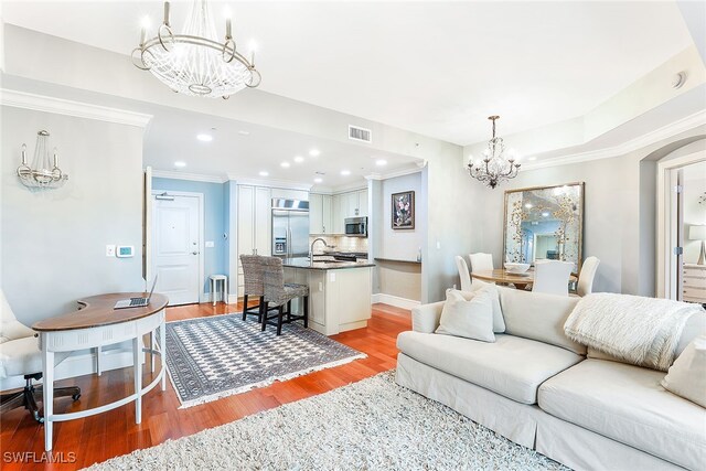 living room featuring crown molding, sink, a chandelier, and light wood-type flooring