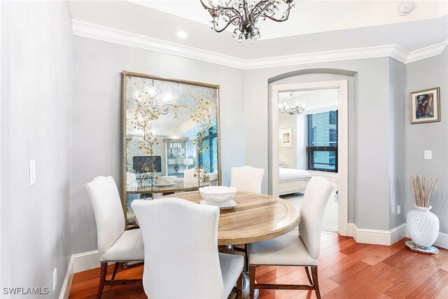 dining room featuring hardwood / wood-style floors, crown molding, and a chandelier