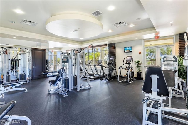 exercise room with french doors and a tray ceiling