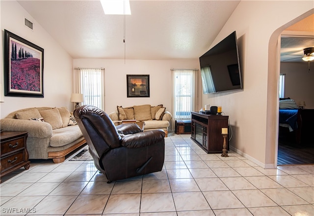 tiled living room with lofted ceiling, ceiling fan, and a wealth of natural light